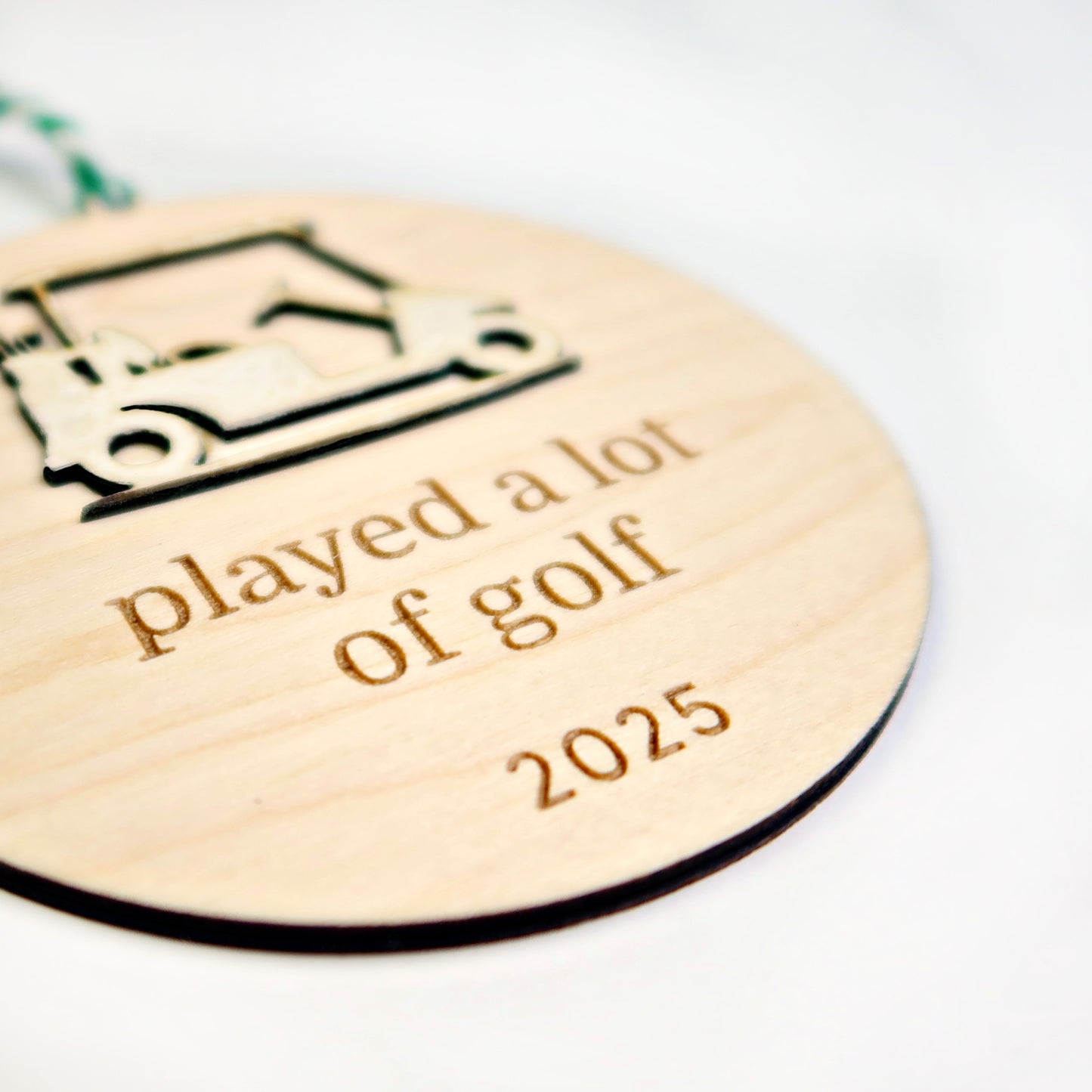 Wooden round ornament with golf cart design and text 'played a lot of golf 2025' on a white background