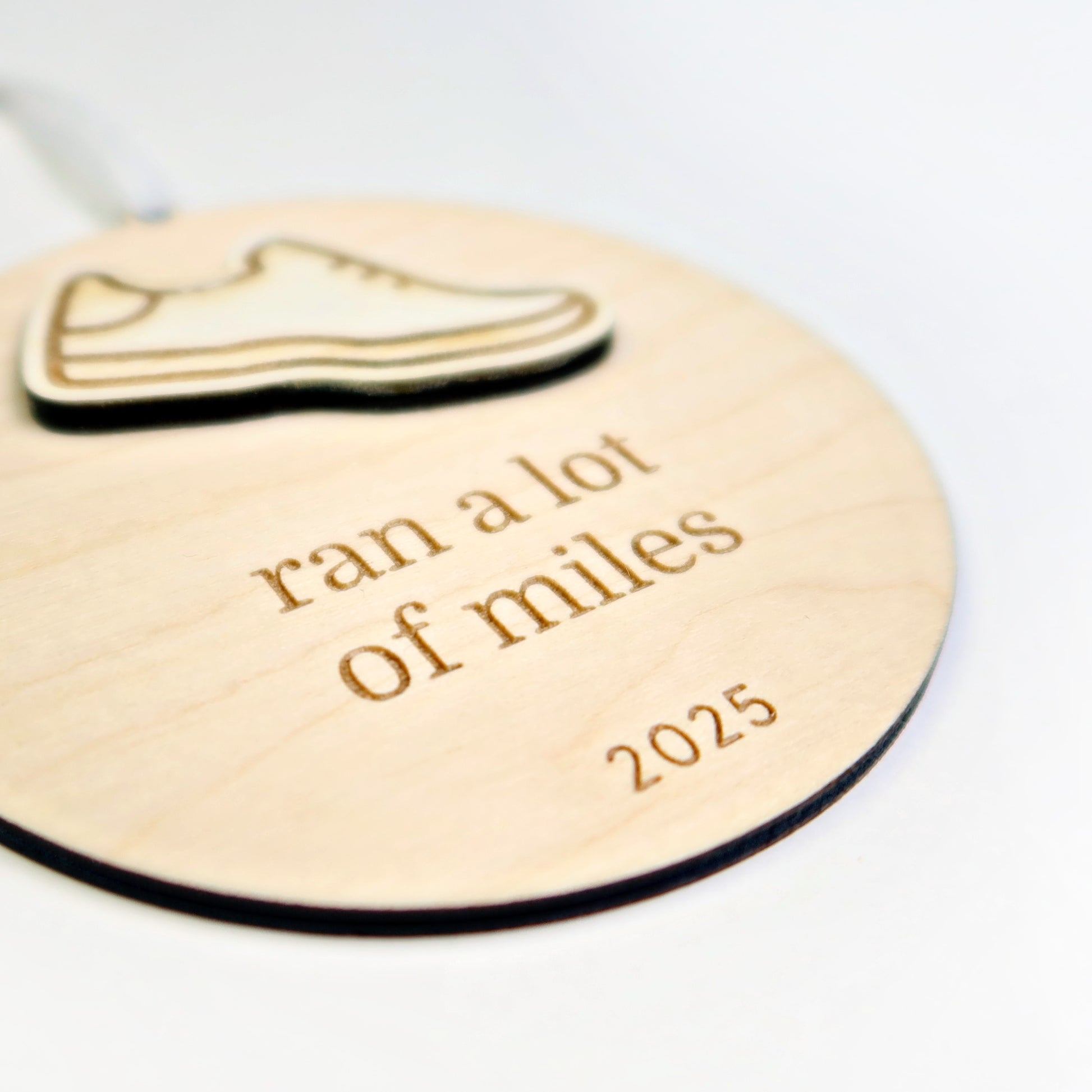 Wooden tag with a shoe icon and text 'ran a lot of miles 2025' on a white background