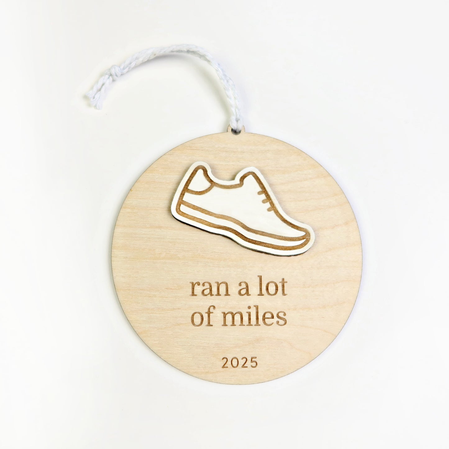 Wooden ornament with a shoe design and text 'ran a lot of miles 2025' on a white background