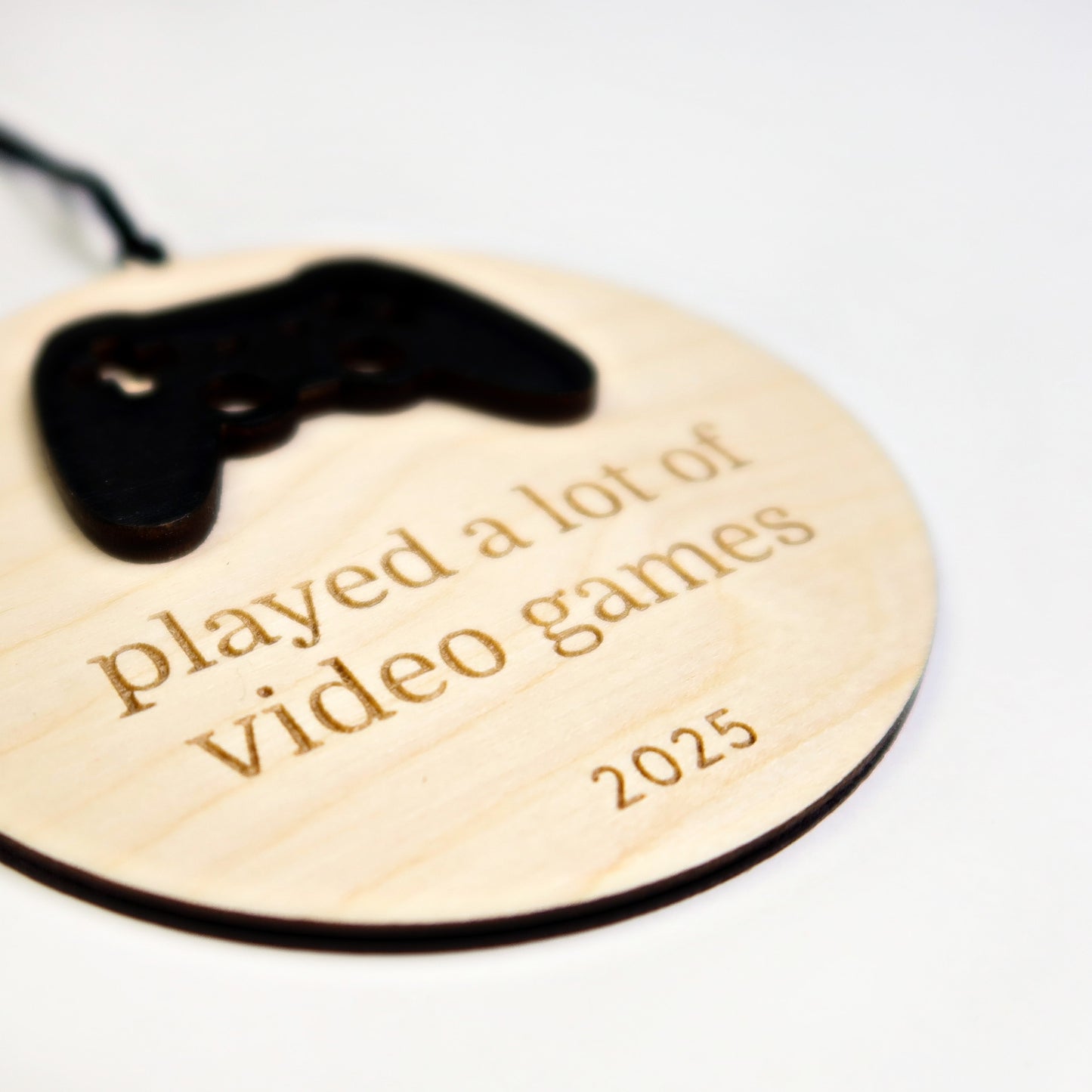 Wooden ornament with game controller design and engraved text on a white background