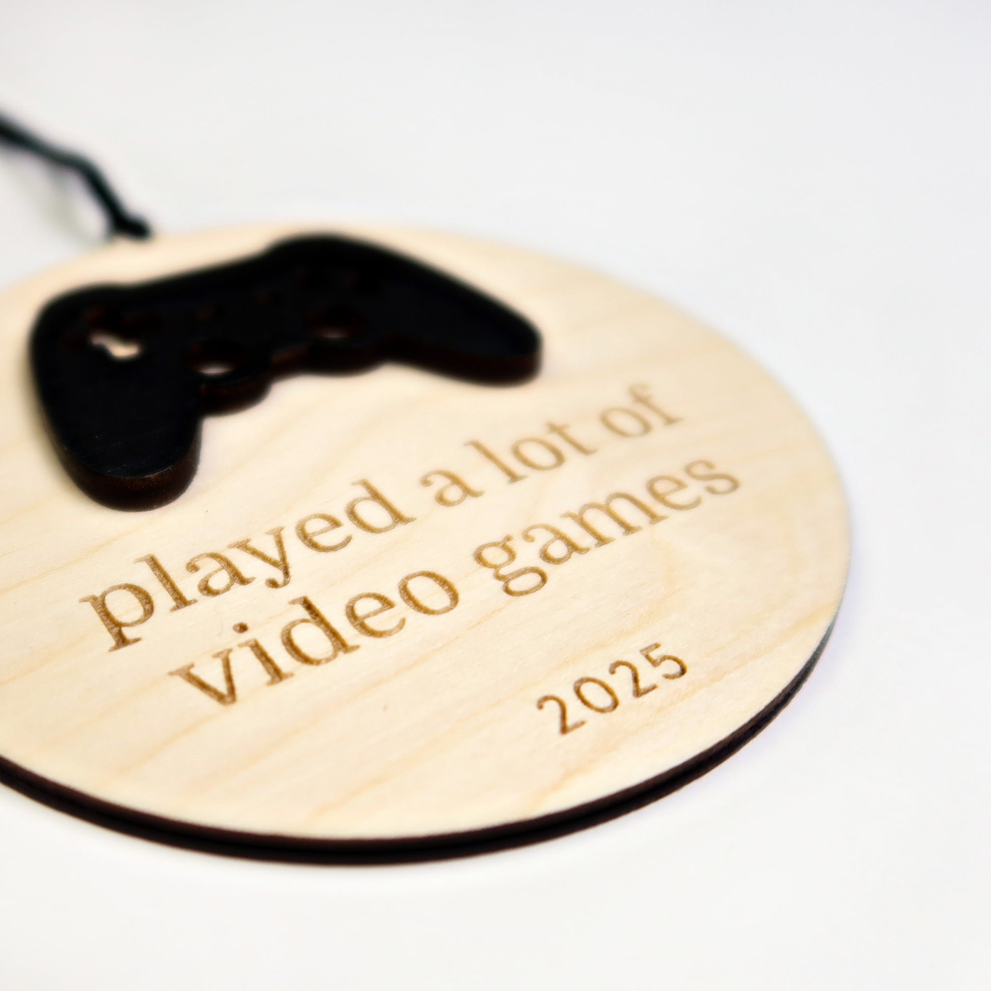 Wooden ornament with game controller design and engraved text on a white background