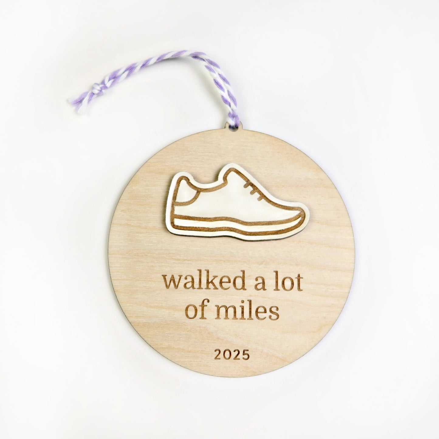Wooden ornament with a shoe design and 'walked a lot of miles 2025' text on a white background