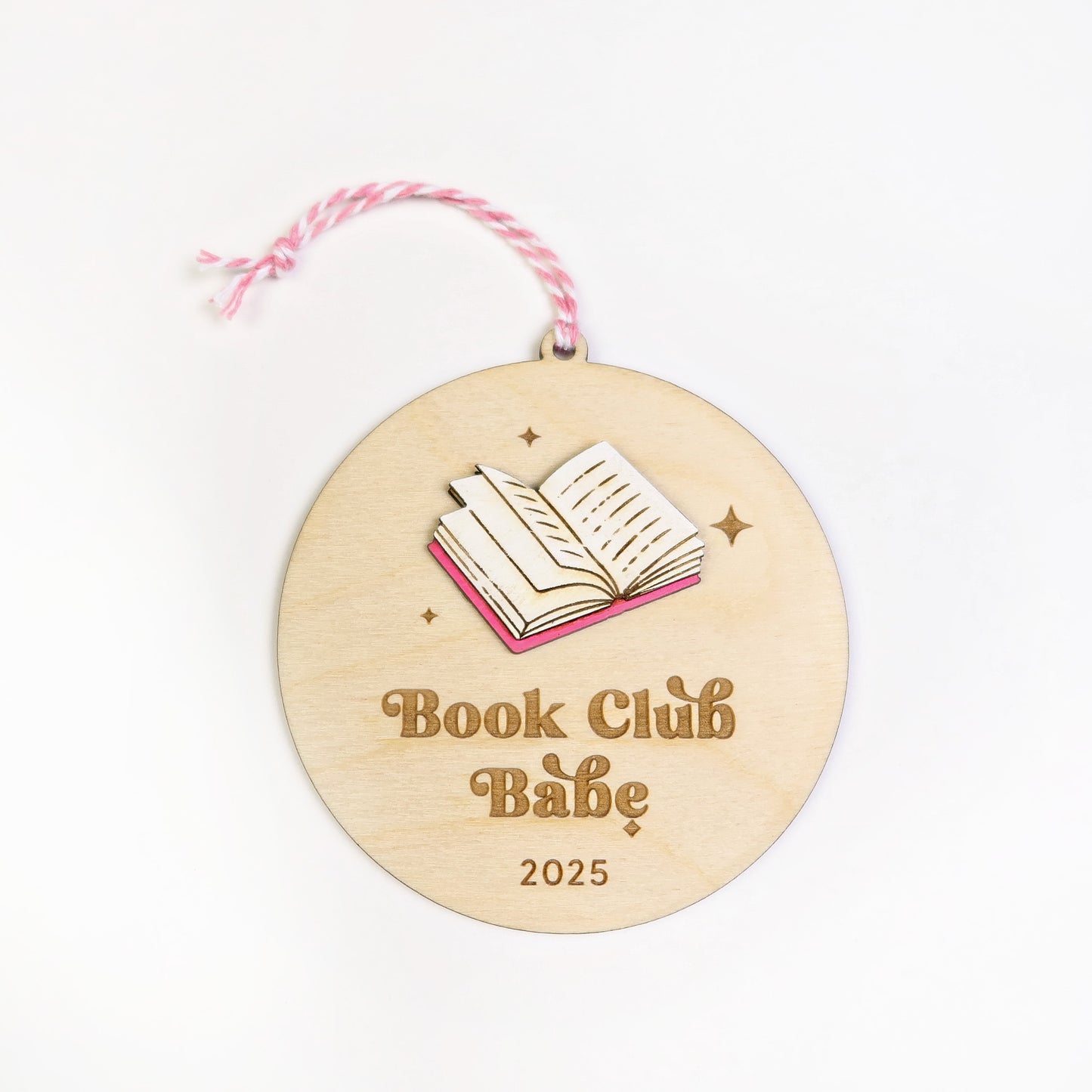 Wooden round ornament with 'Book Club Babe 2025' text and book illustration on a white background.