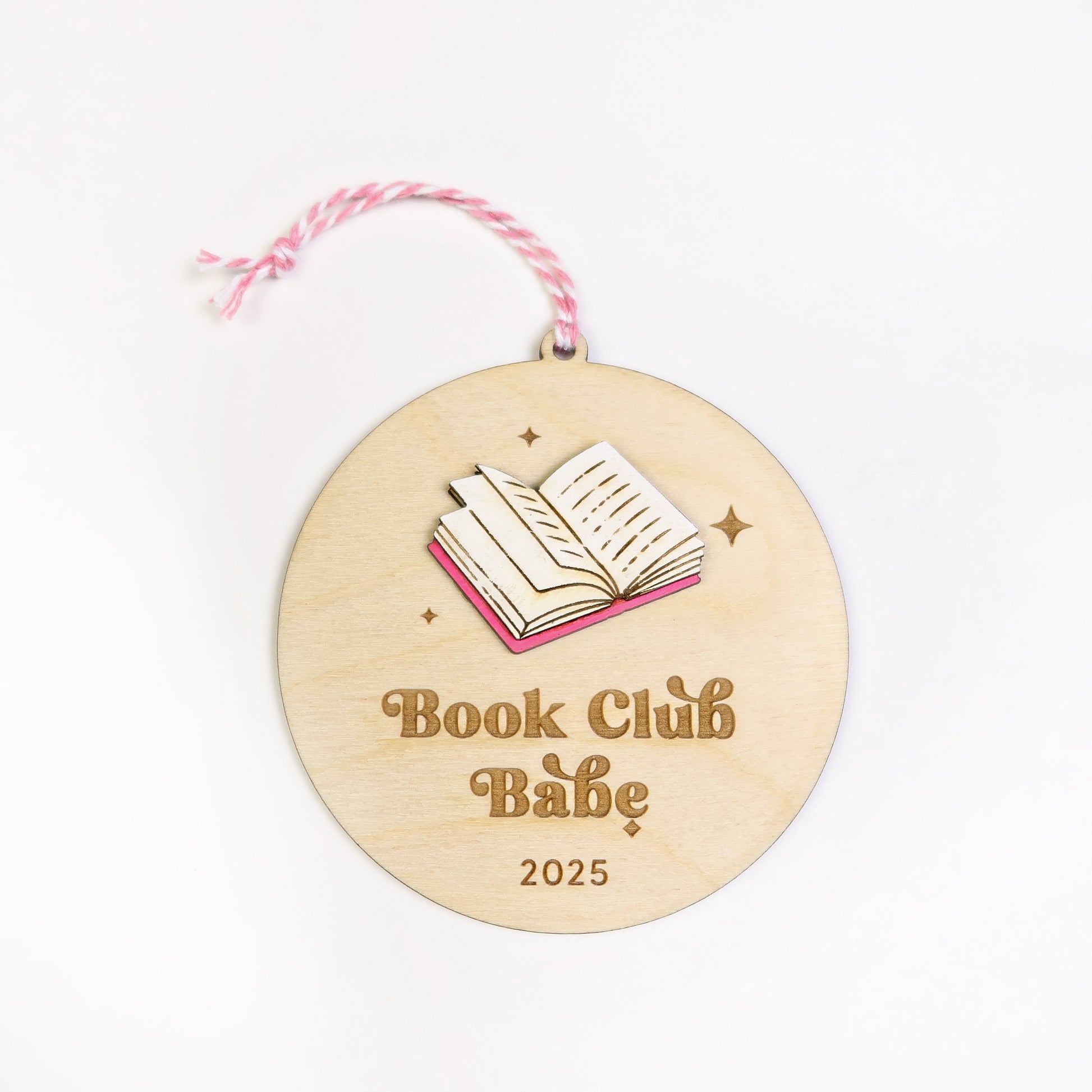 Wooden round ornament with 'Book Club Babe 2025' text and book illustration on a white background.