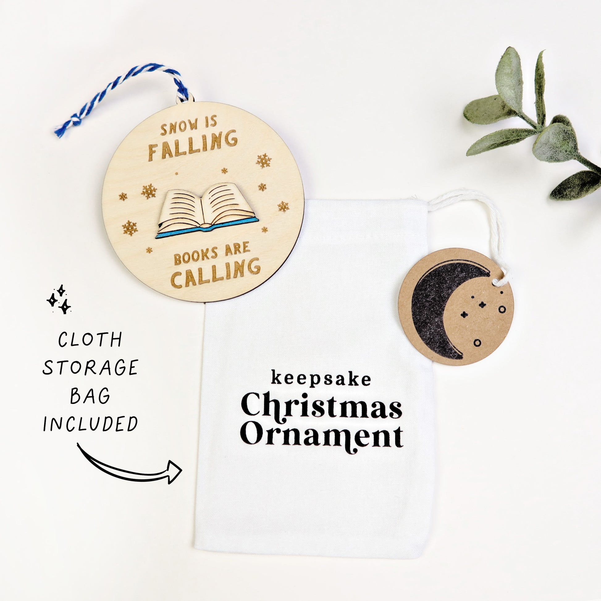 Wooden Christmas ornament with text 'Snow is falling, books are calling' on a white background.