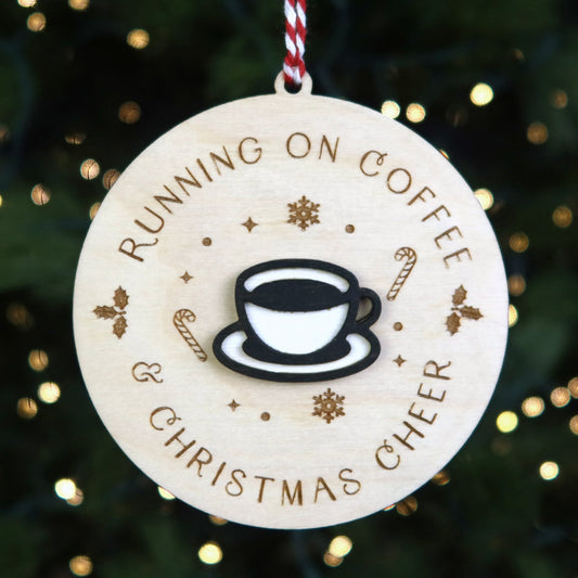 Decorative Christmas ornament with a coffee cup design and text 'Running on Coffee & Christmas Cheer' against a festive background.