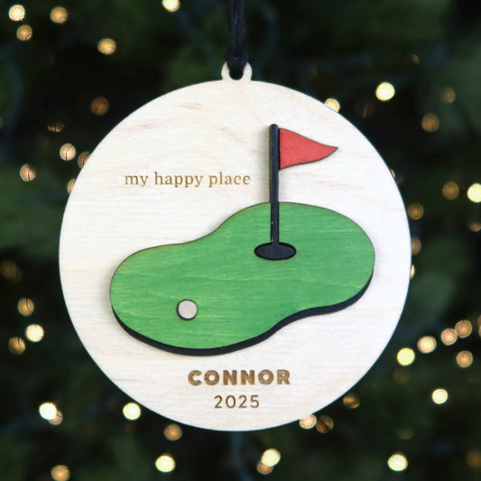 Decorative ornament with golf course design and text 'my happy place" with custom name and date engraved
