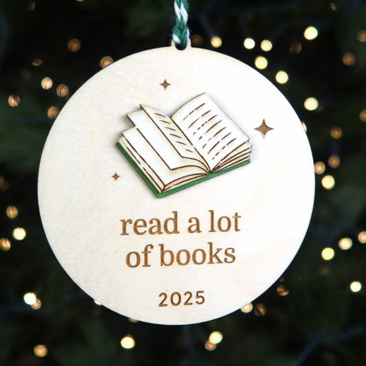 Decorative ornament with book illustration and 'read a lot of books 2025' text on a Christmas tree.