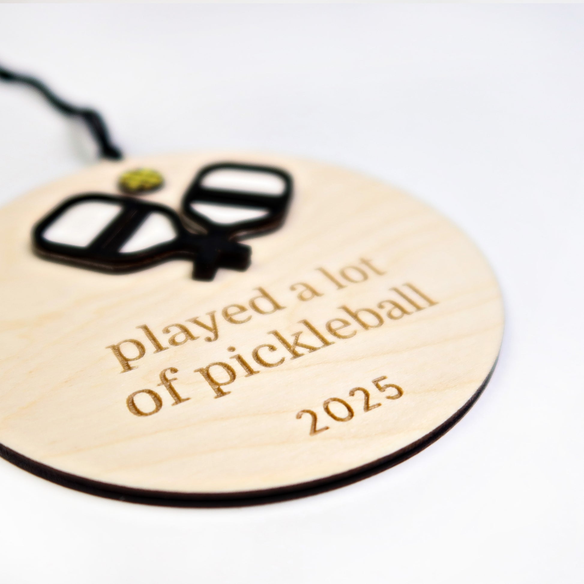 Wooden ornament with pickleball paddle design and text 'played a lot of pickleball 2025' on a white background