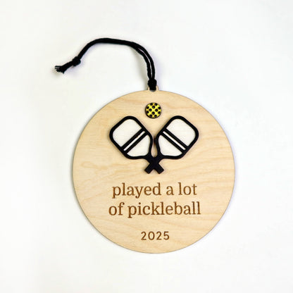 Wooden ornament with pickleball design and text 'played a lot of pickleball 2025' on a white background