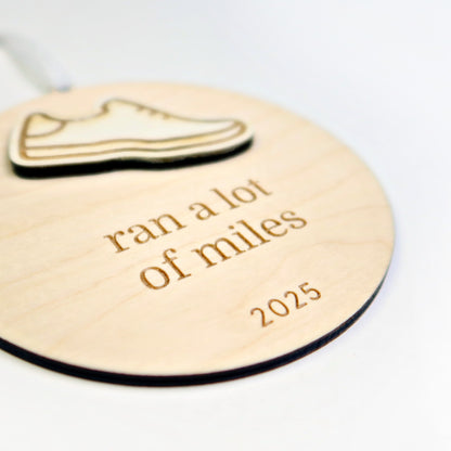 Wooden tag with a shoe icon and text 'ran a lot of miles 2025' on a white background