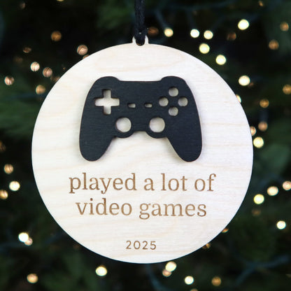 Decorative ornament with a gaming controller cutout and text 'played a lot of video games 2025' on a Christmas tree.