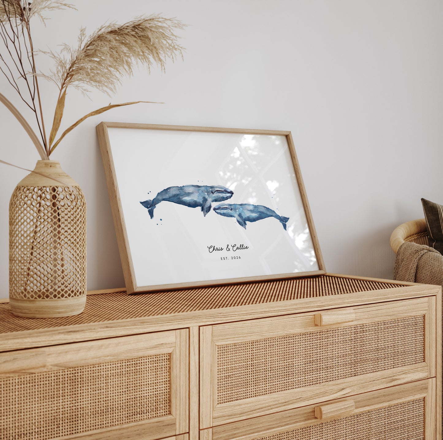 Framed artwork of two whales on a wooden cabinet with decorative elements.